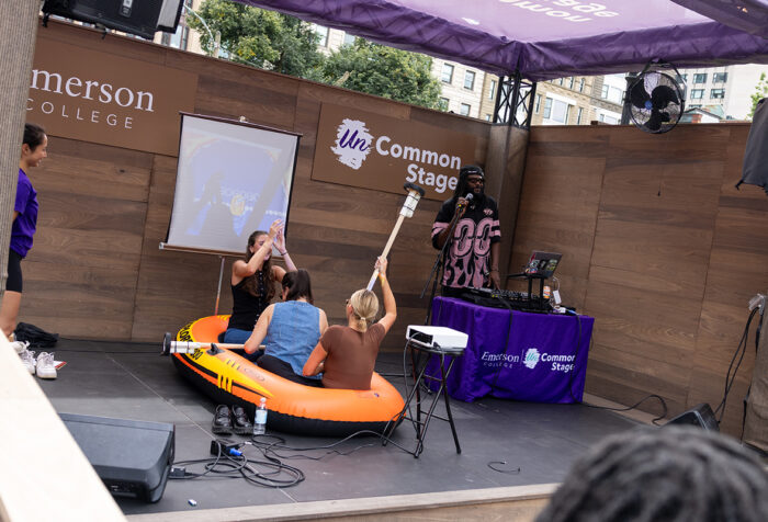 people sit in an inflatable rowboat on an outdoor stage