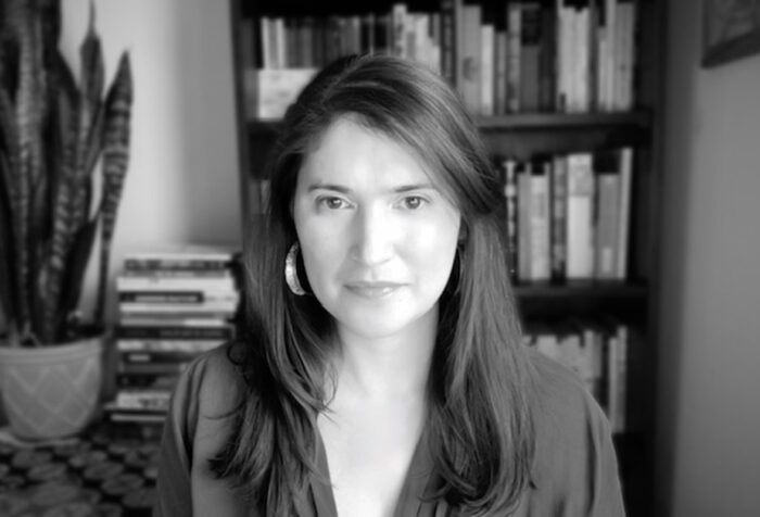 black and white photo of woman with long straight hair, wearing v-neck top, hoop earrings