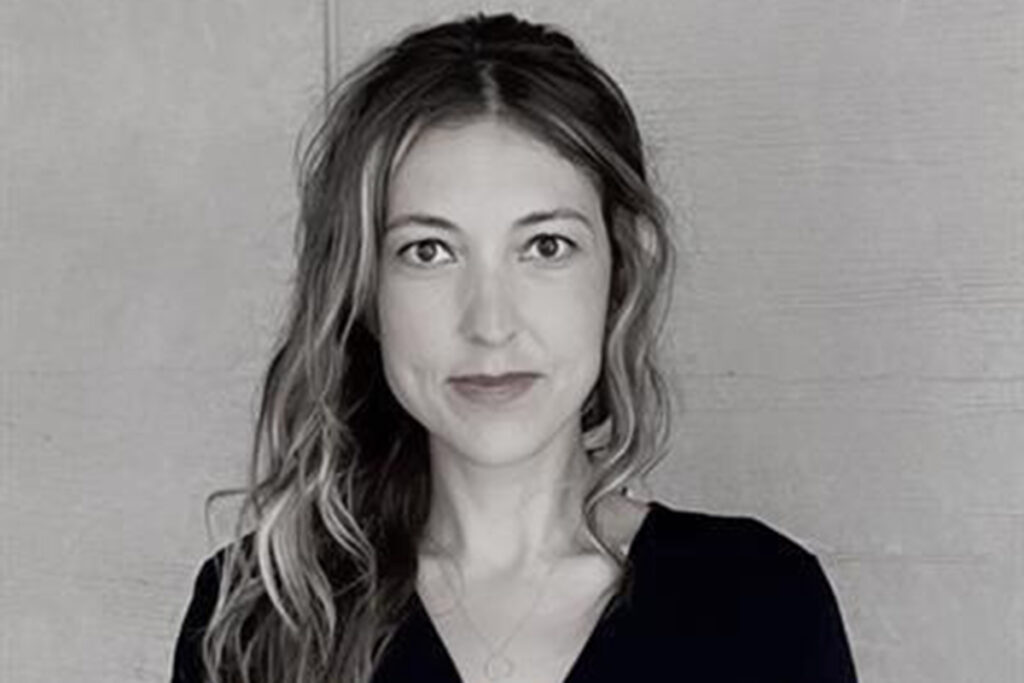 black and white photo of woman with long wavy highlighted hair, wearing a dark v-neck top