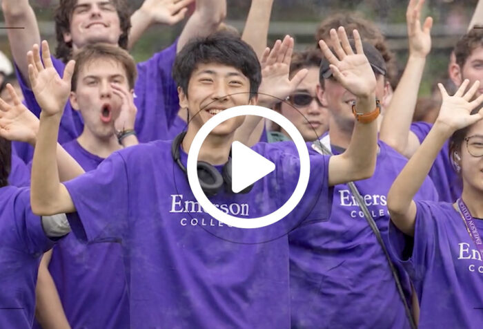 students in purple Emerson t-shirts wave hands in air