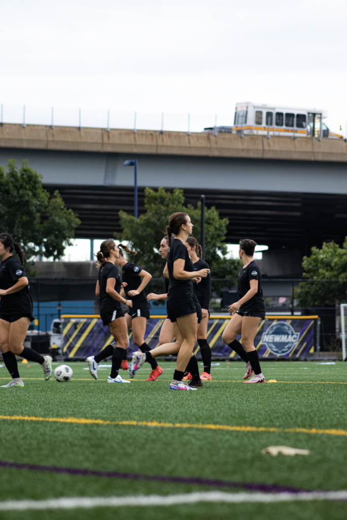 Players run with a highway in the background