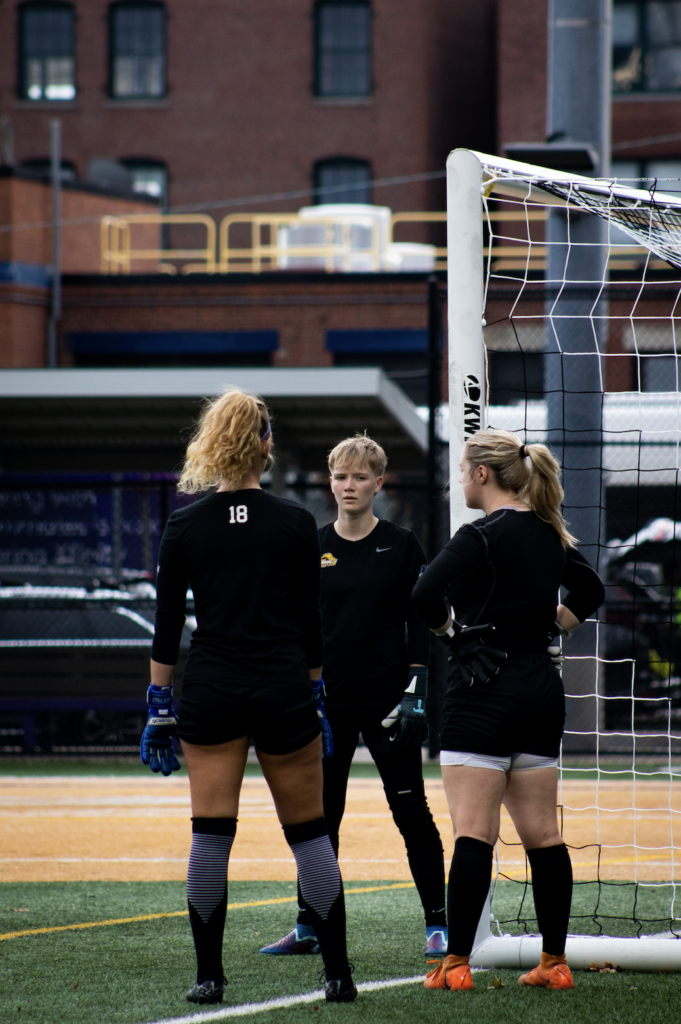 Three women's team players talk during practice.