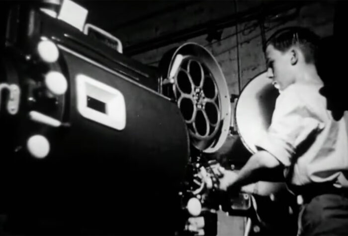 black and white footage of a person working a projector