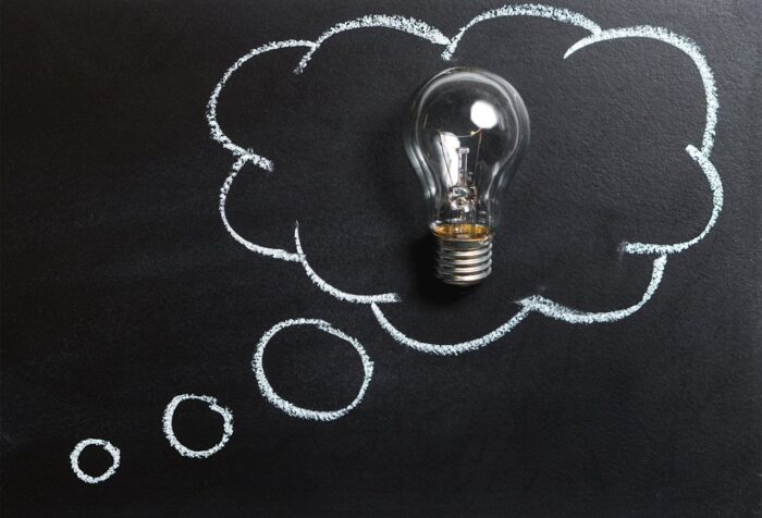 A lightbulb in a thought cloud, with a black background.