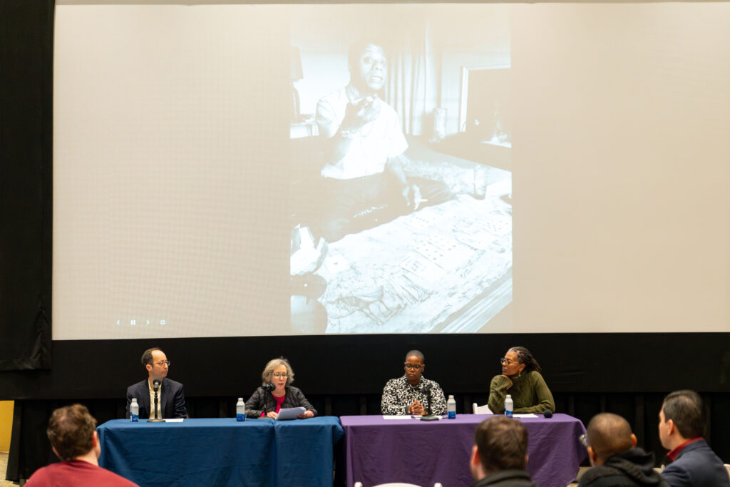 Timur Pakay, Kathy Pakay,  Novuyo Tshuma, Kimberly McLarin discuss the movie with a picture of James Baldwin projected behind them as they sit at a table