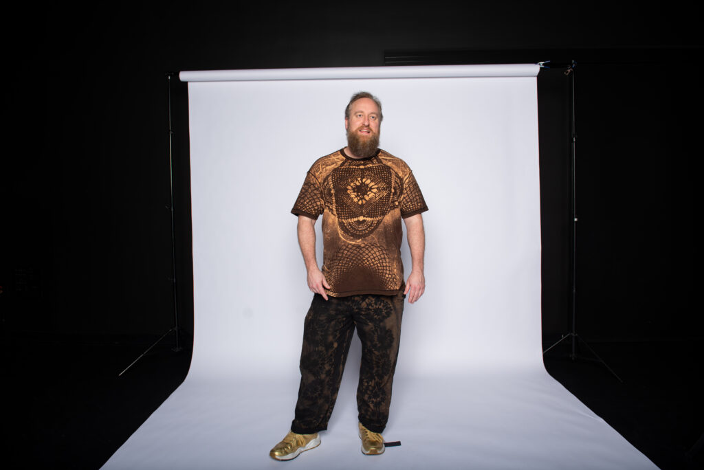 Justin Ramey posing with a white backdrop in studio