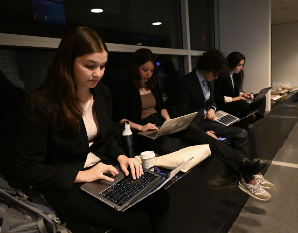 Four correspondents working on laptops while sitting on the ground