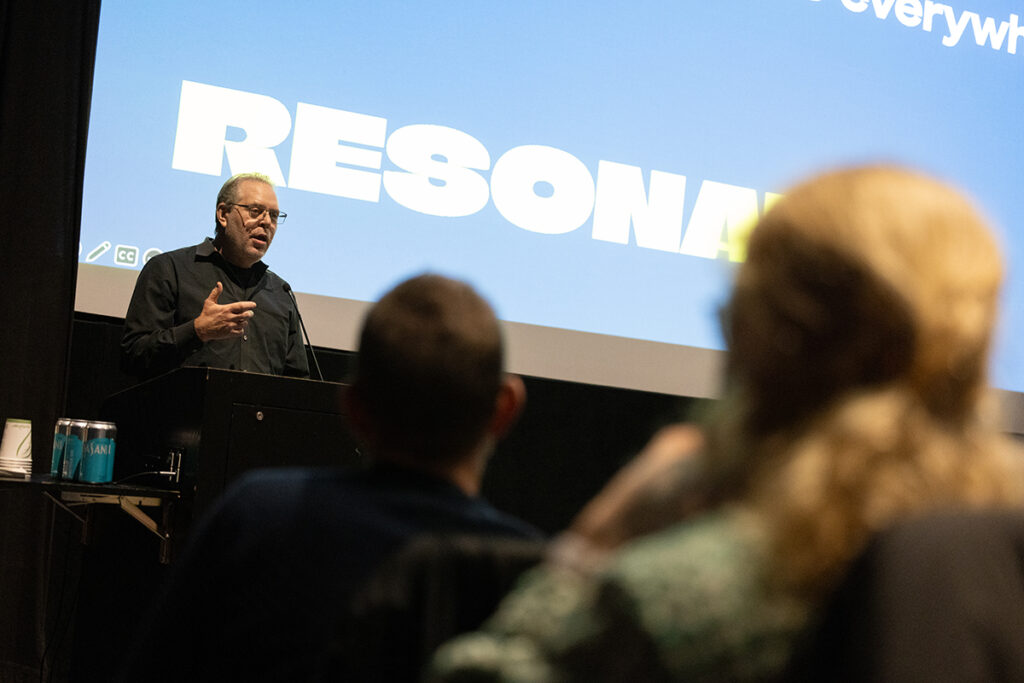 Boaz Paldi stands before screen reading the word "resonate"