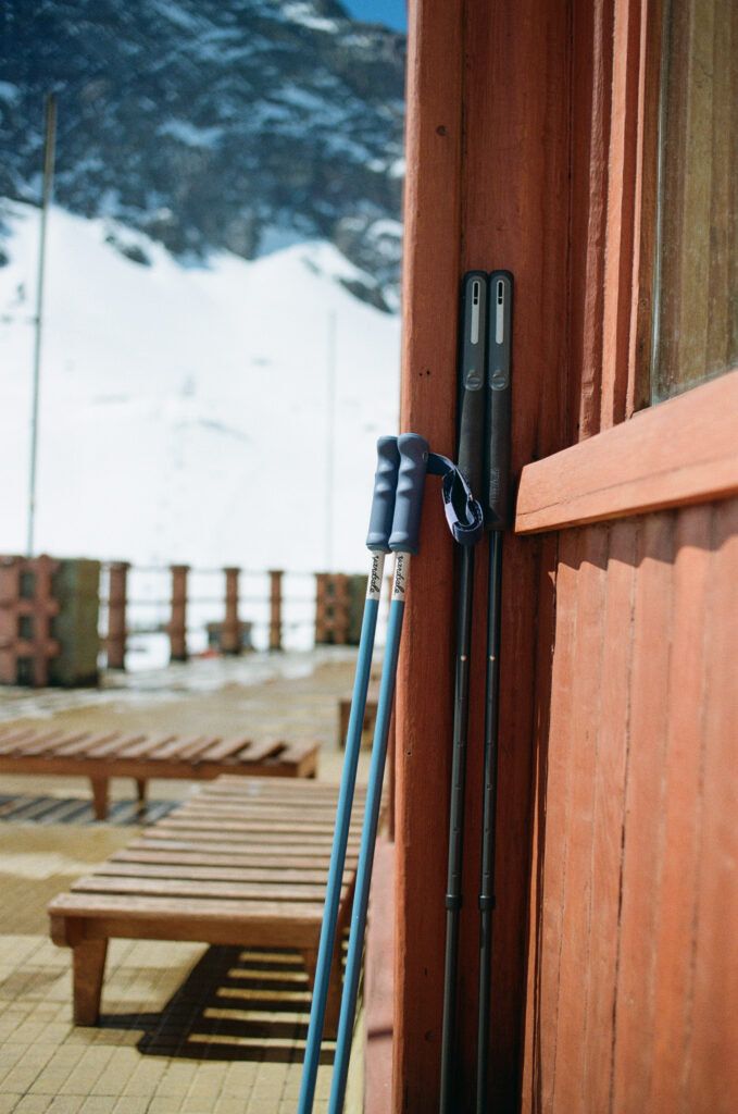 A pair of ski poles lean against a wall outside