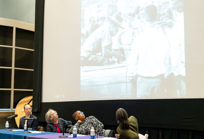 Panelists look at image of James Baldwin behind them