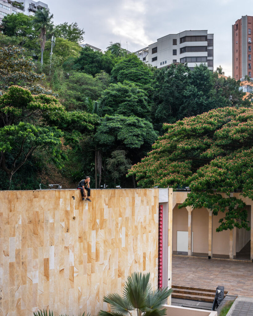 A man sits alone atop a large wall with no one near him