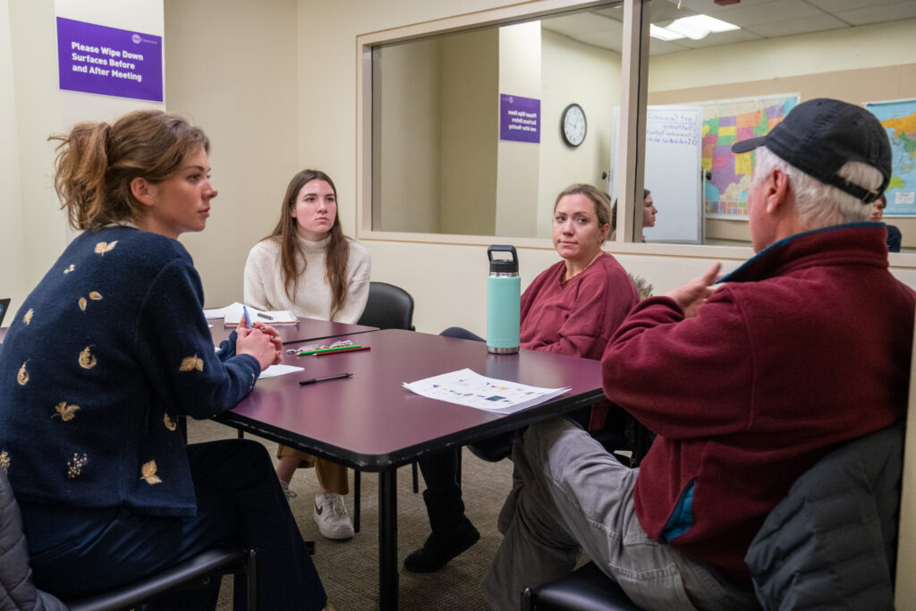 Four people sit around a table during a group therapy session