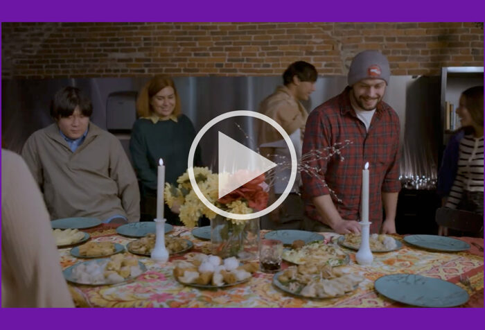 Friends gather around a table covered with food, candles