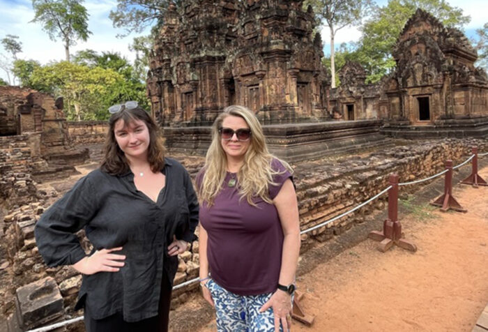 Two women stand in front of a Cambodian temple