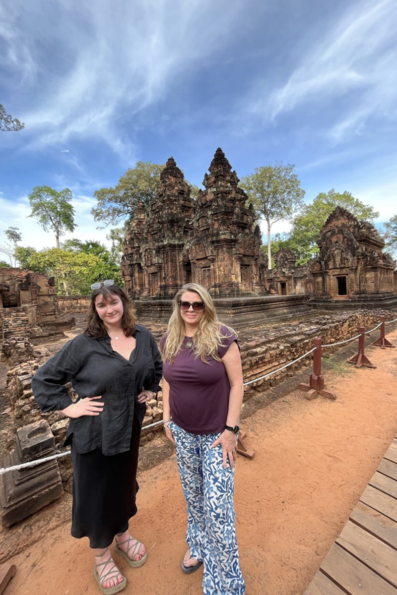 Two women stand in front of Cambodian temple