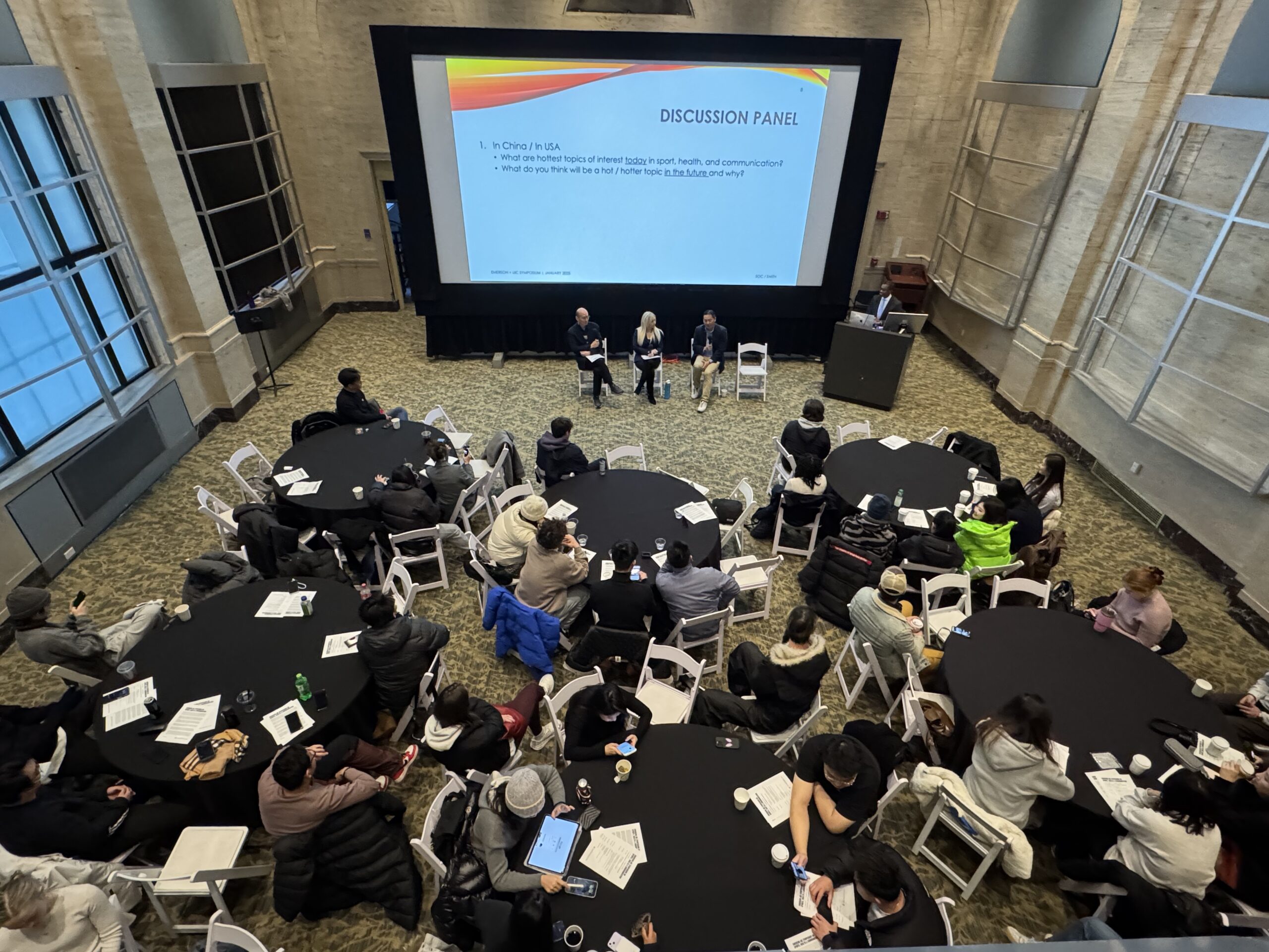 Taken from above of Bordy Theater showing students at tables, Scholars from Emerson and UIC debate AI’s role in balancing athlete performance with emotional and physical well-being during the panel discussion. [Photo/Molly Loughman]