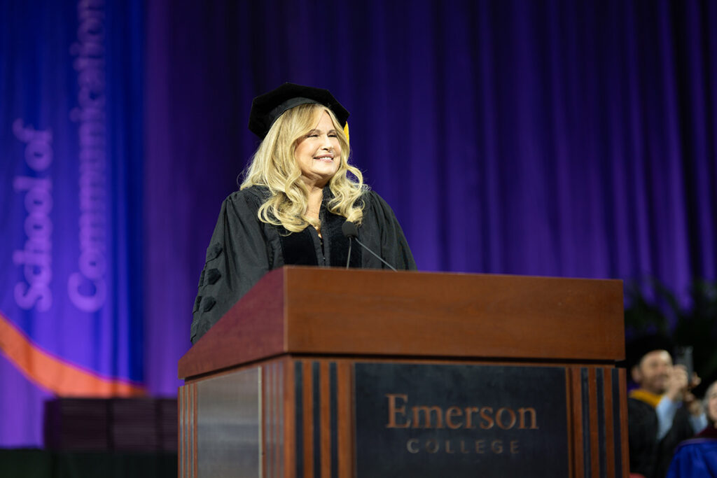 Jennifer Coolidge in cap and gown at podium