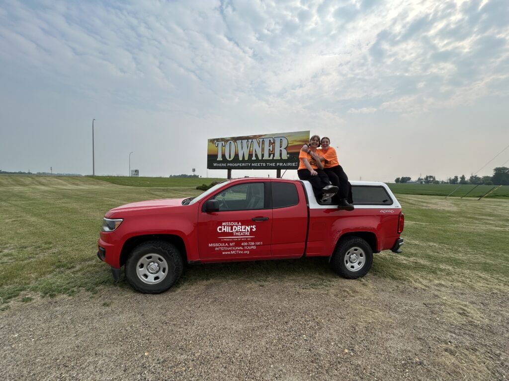 Amelia Duval and another person sit atop a red truck
