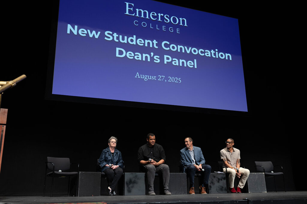One woman, three men sit on stage below screen reading "New Student Convocation Dean's Panel"