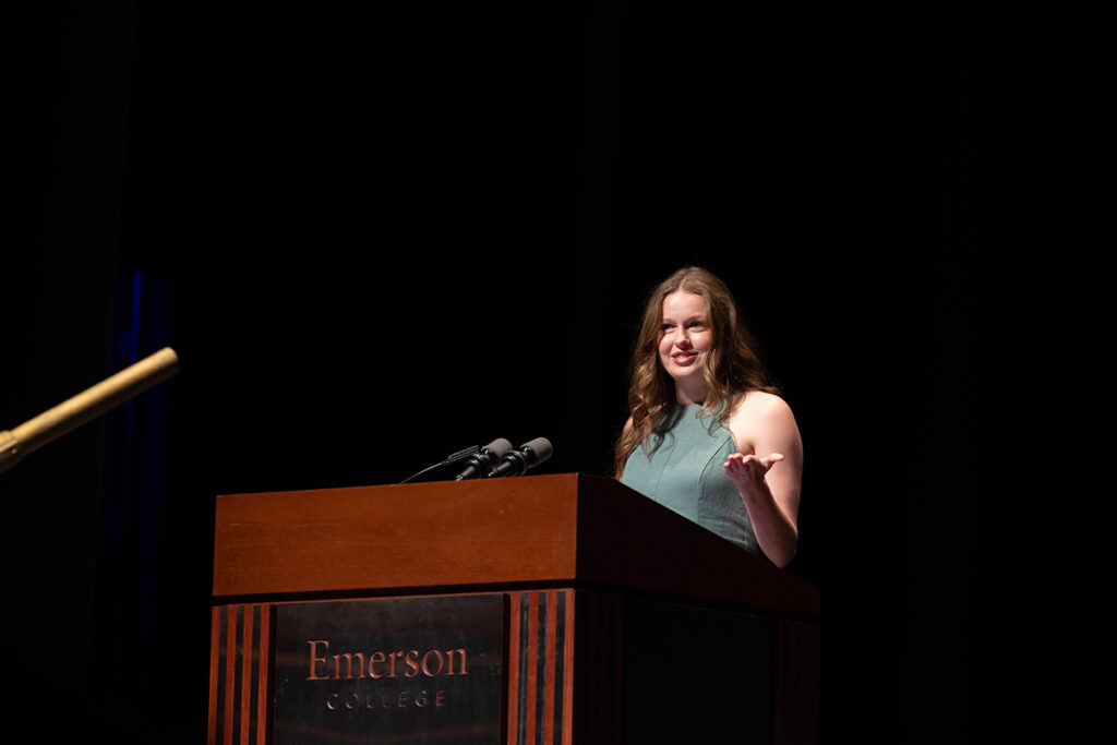 Student in green sleeveless top, long hair speaks at podium
