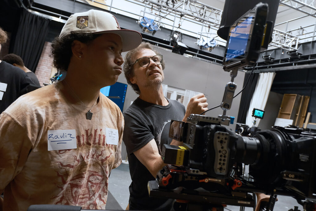 man looks at monitor on camera as young man watches