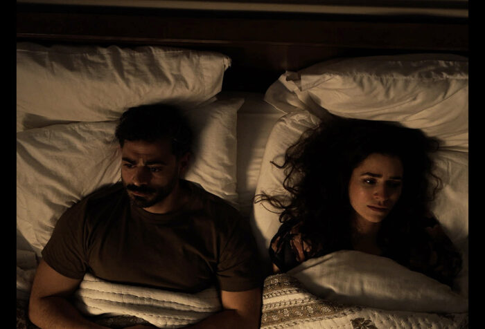 Two people lay in bed facing opposite sides