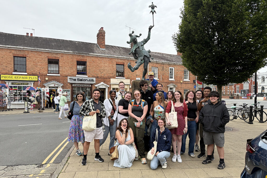 Students pose for a photo in front of a statue of a jester