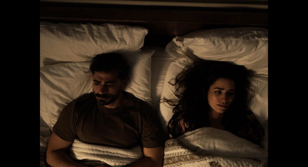 Two people lay in bed looking away from each other