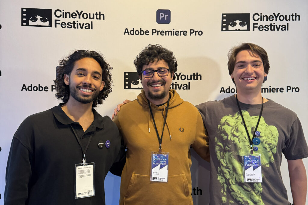 Three people stand together posing for a photo