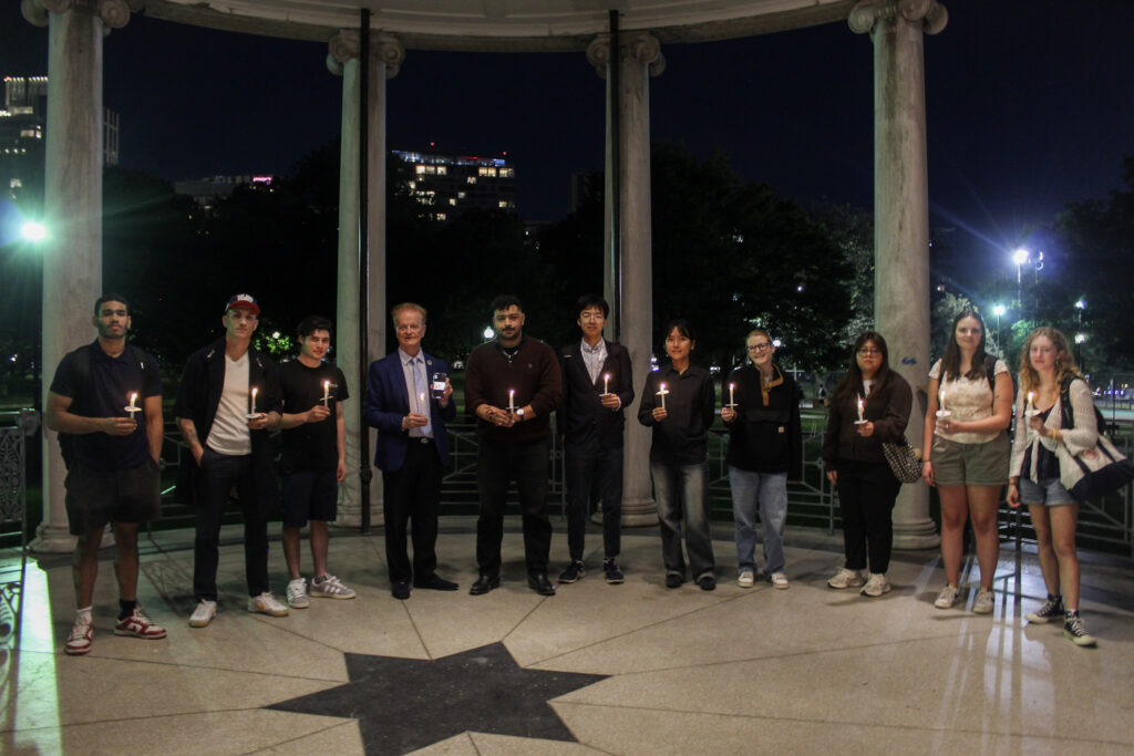 People stand in the Boston Common bandstand holding candles