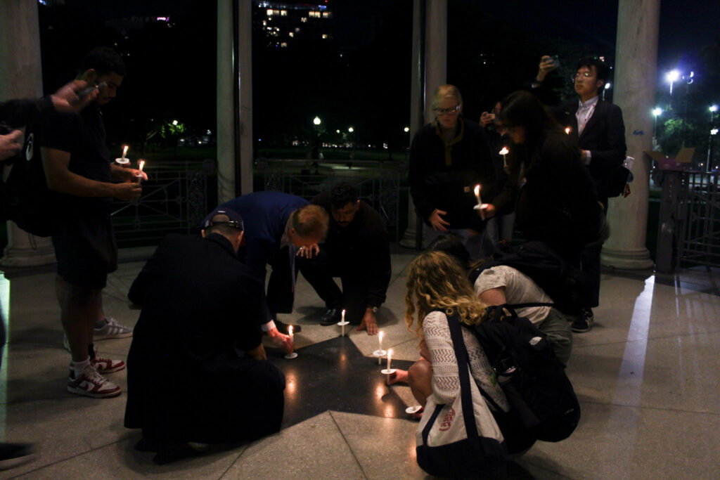 Individuals place candles on the ground