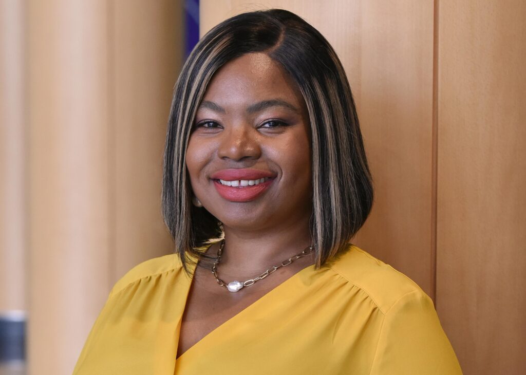 A person wearing a yellow shirt smiles at the camera.