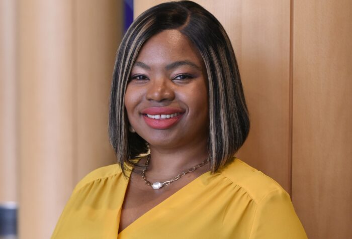 A person wearing a yellow shirt smiles at the camera.