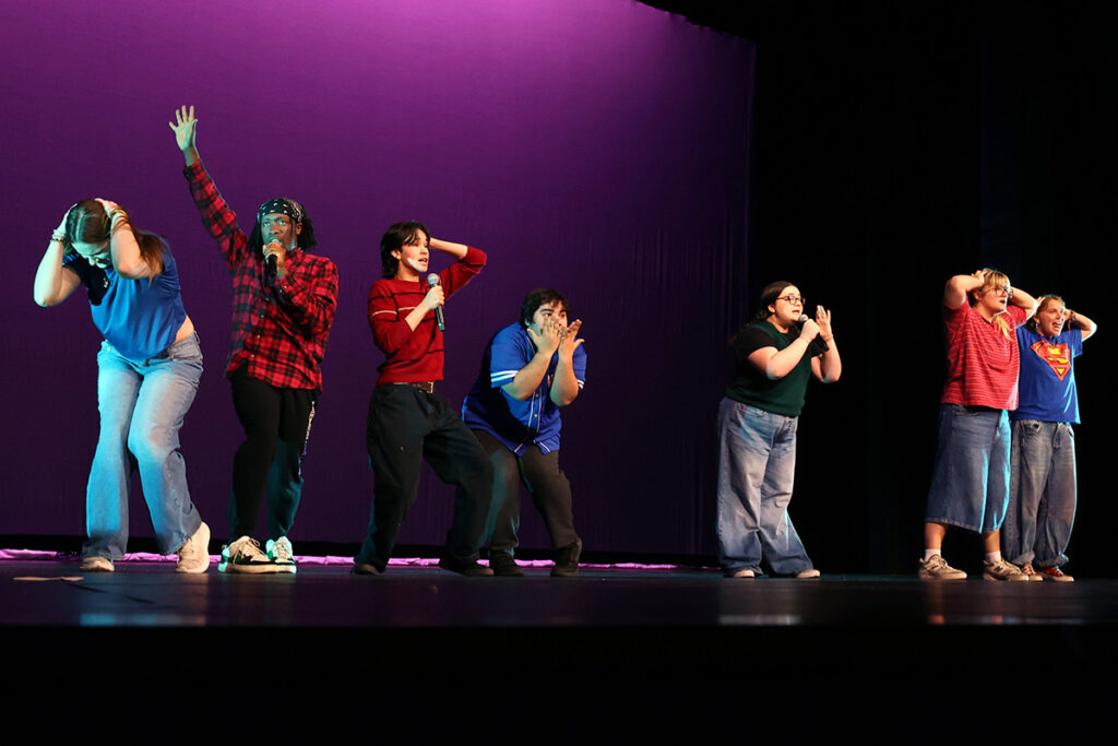 Actors make different exaggerated gestures on stage