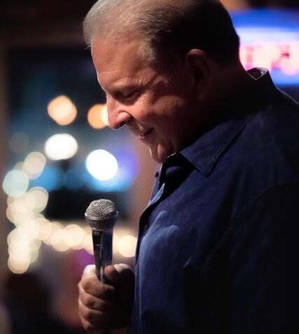 A side profile of a person holding a microphone and smiling.