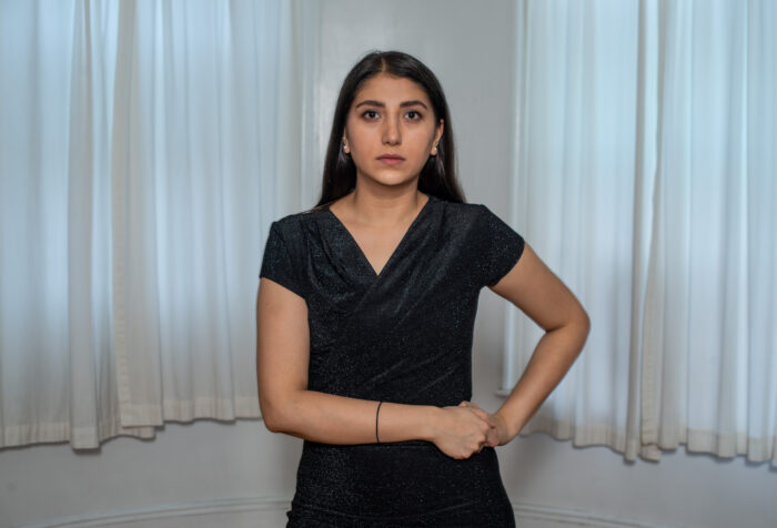 A person wearing a dress poses for a photo, both arms on one hip.