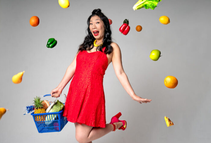 Woman in red dress holds grocery basket as fruit swirls around her