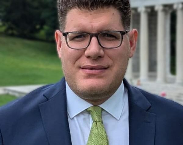 A man wearing a suit looks at the camera.