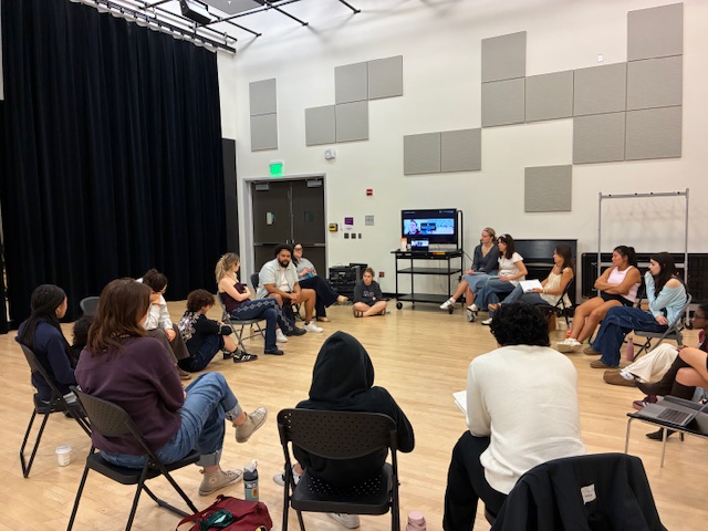 People sit in chairs and on the floor in a circule
