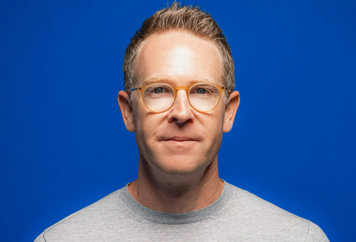 Sam Presti headshot with a blue background