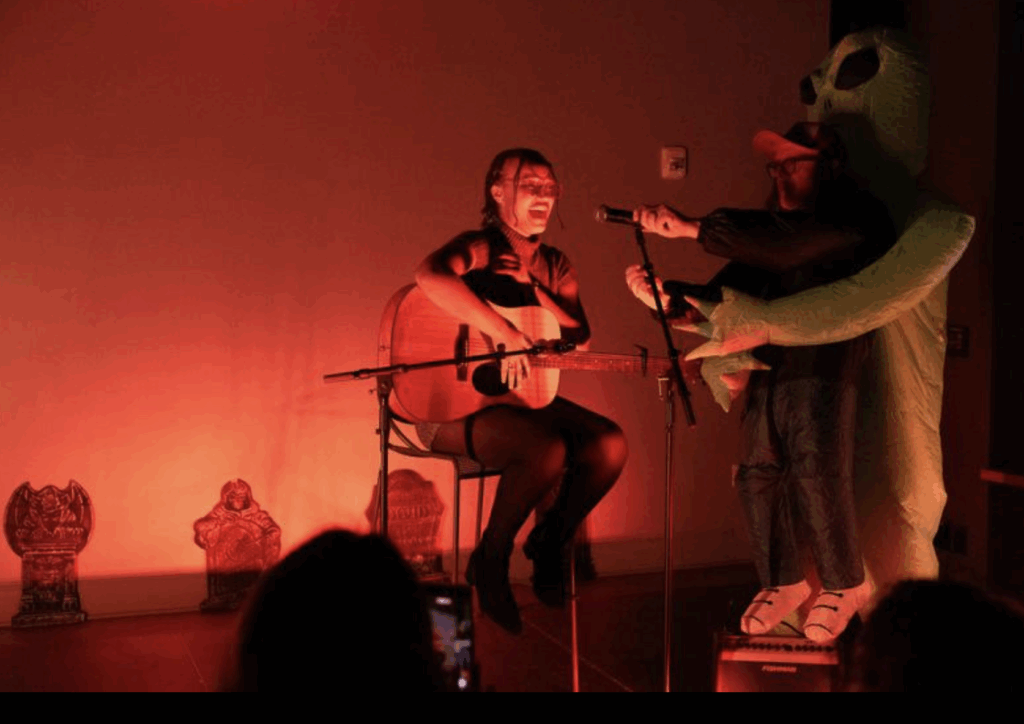 A person plays guitar while sitting on stage