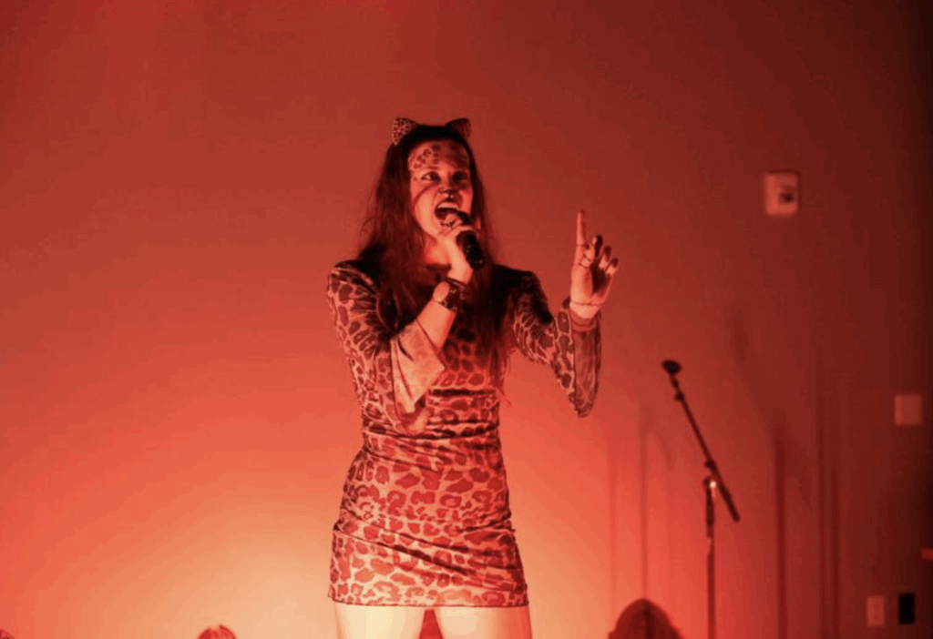 A person talks onstage while dressed as a leopard