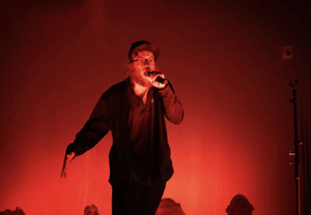 A person on stage talks while holding a microphone