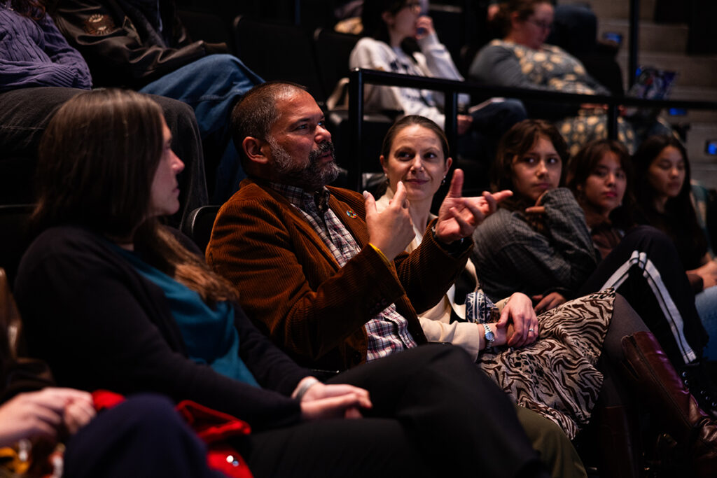 man sitting in the audience gestures
