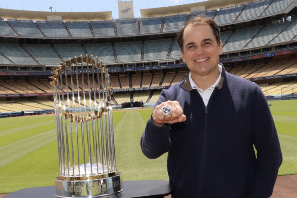 tim neverett shows off World Series ring next to World Series trophy in Dodger Stadium