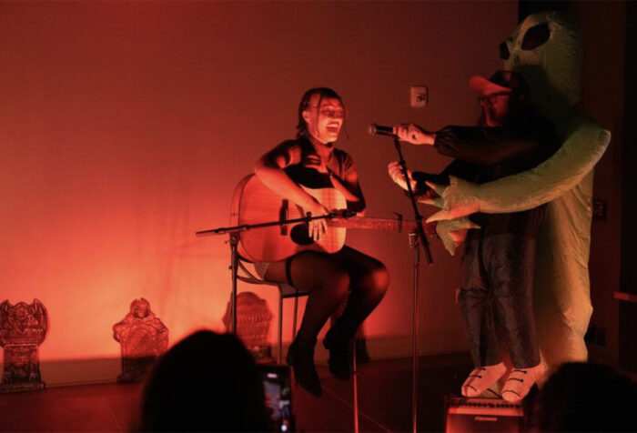 A person sings on stage while a person in a costume hold sa microphone for them to sing
