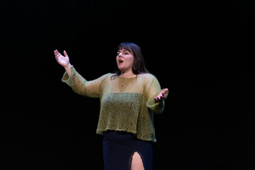 A person speaks with arms open on stage
