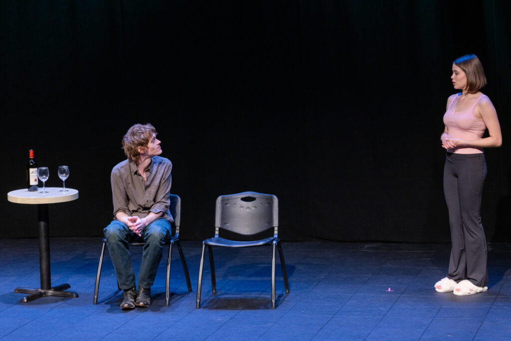 A person sits in a chair while another person is 10 feet away from them standing, as they look at each other
