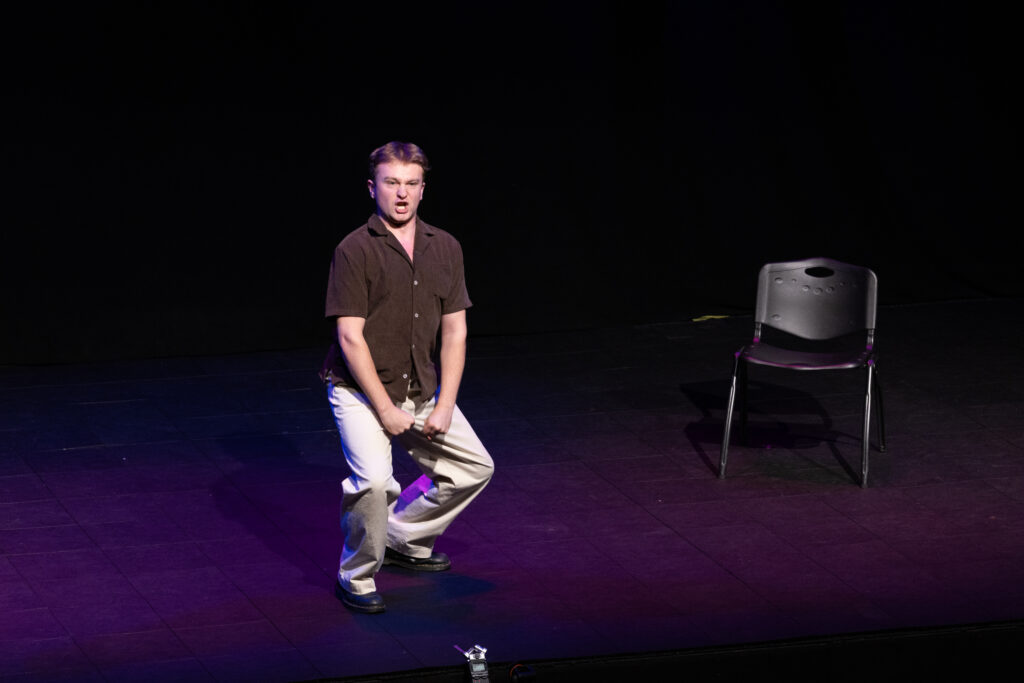 A person sits on a stool on stage
