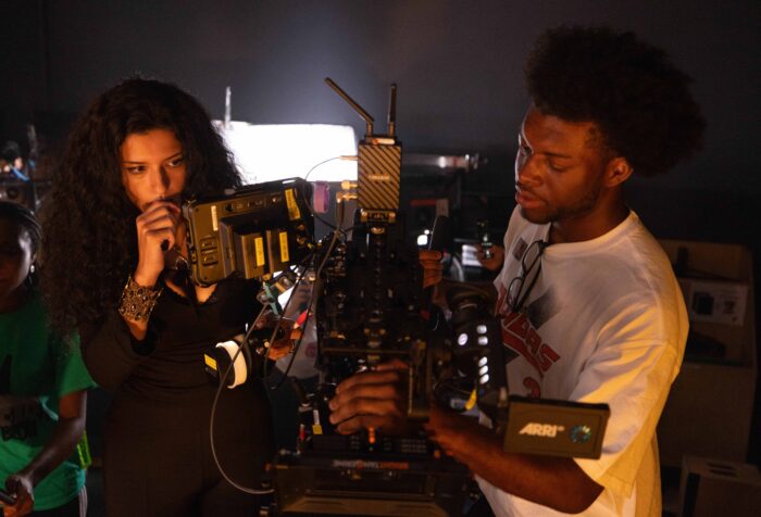 Two people examine a camera, preparing to film